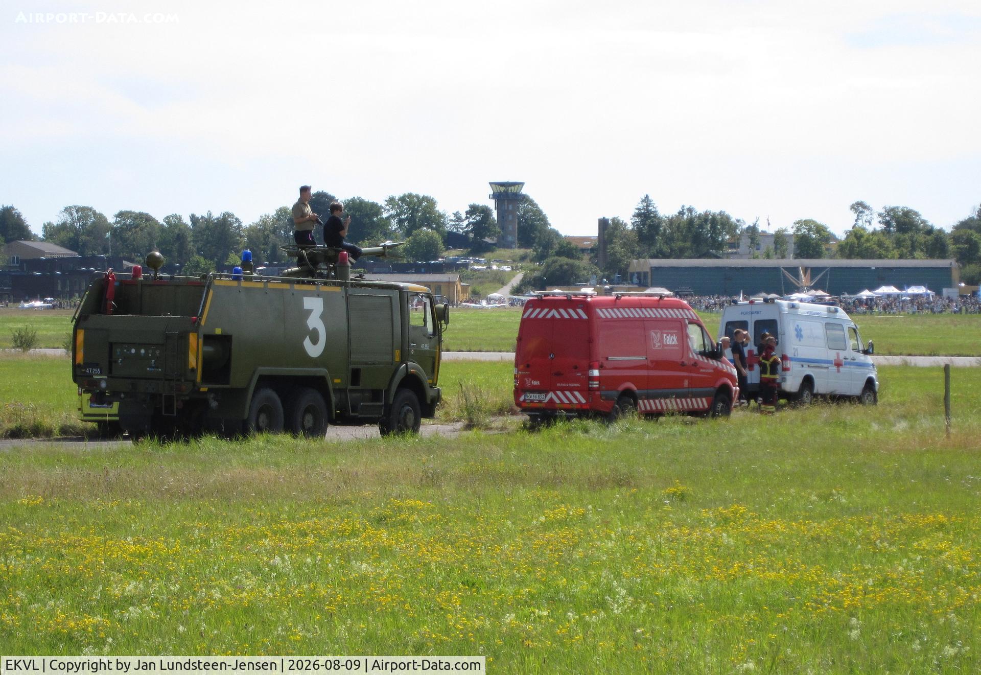 Værløse Air Base Airport, A green air force fire truck, a red Falck rescue van and a white military ambulance on standby at an airshow at the former Vaerloese Air Base in Denmark. Control tower and Hangar 1 in background., photo by Jan Lundsteen-Jensen